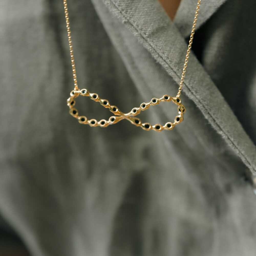 Delicate gold infinity pendant necklace with black accents, perfect for everyday elegance.
