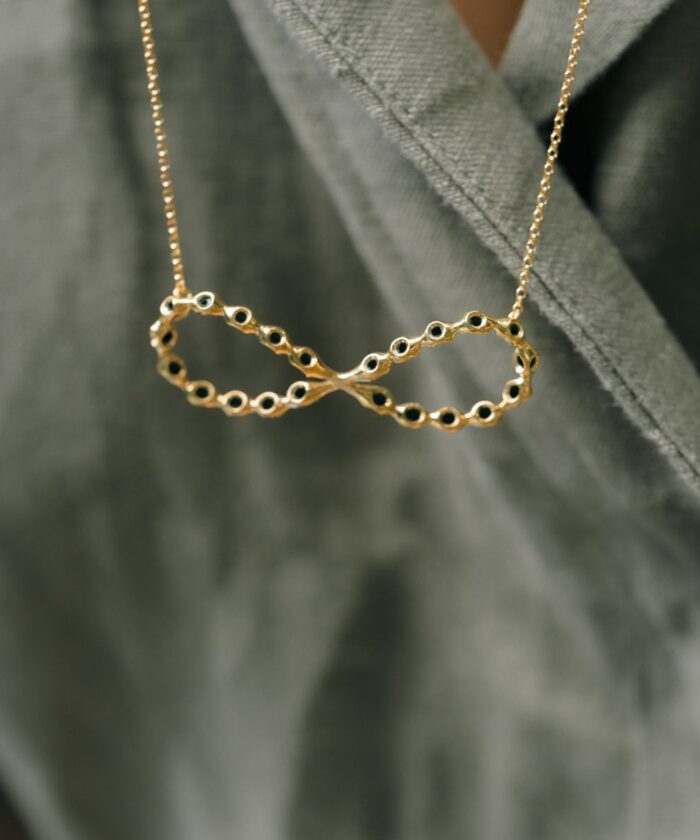 Delicate gold infinity pendant necklace with black accents, perfect for everyday elegance.