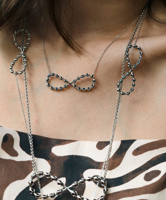 Elegant silver infinity pendant necklace with black accents for women.
