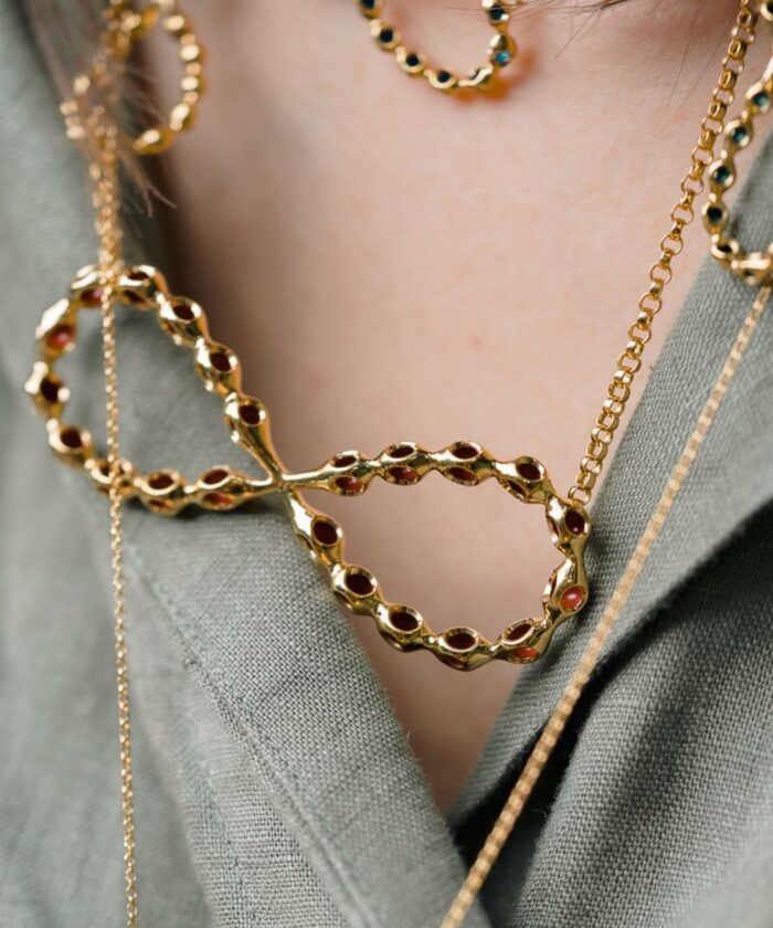 Elegant gold infinity pendant necklace with a modern design and intricate chain details. Perfect for stylish accessories.