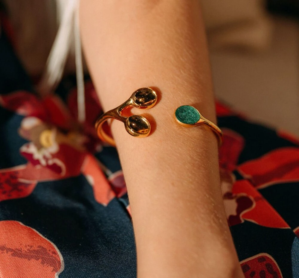 Elegant golden bracelet with turquoise accent on a woman's wrist.
