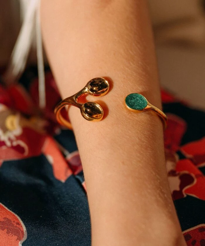 Elegant golden bracelet with turquoise accent on a woman's wrist.