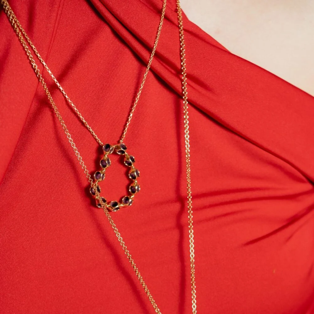 Elegant gold pendant necklace featuring purple gemstones, perfect for adding glamour to any outfit.