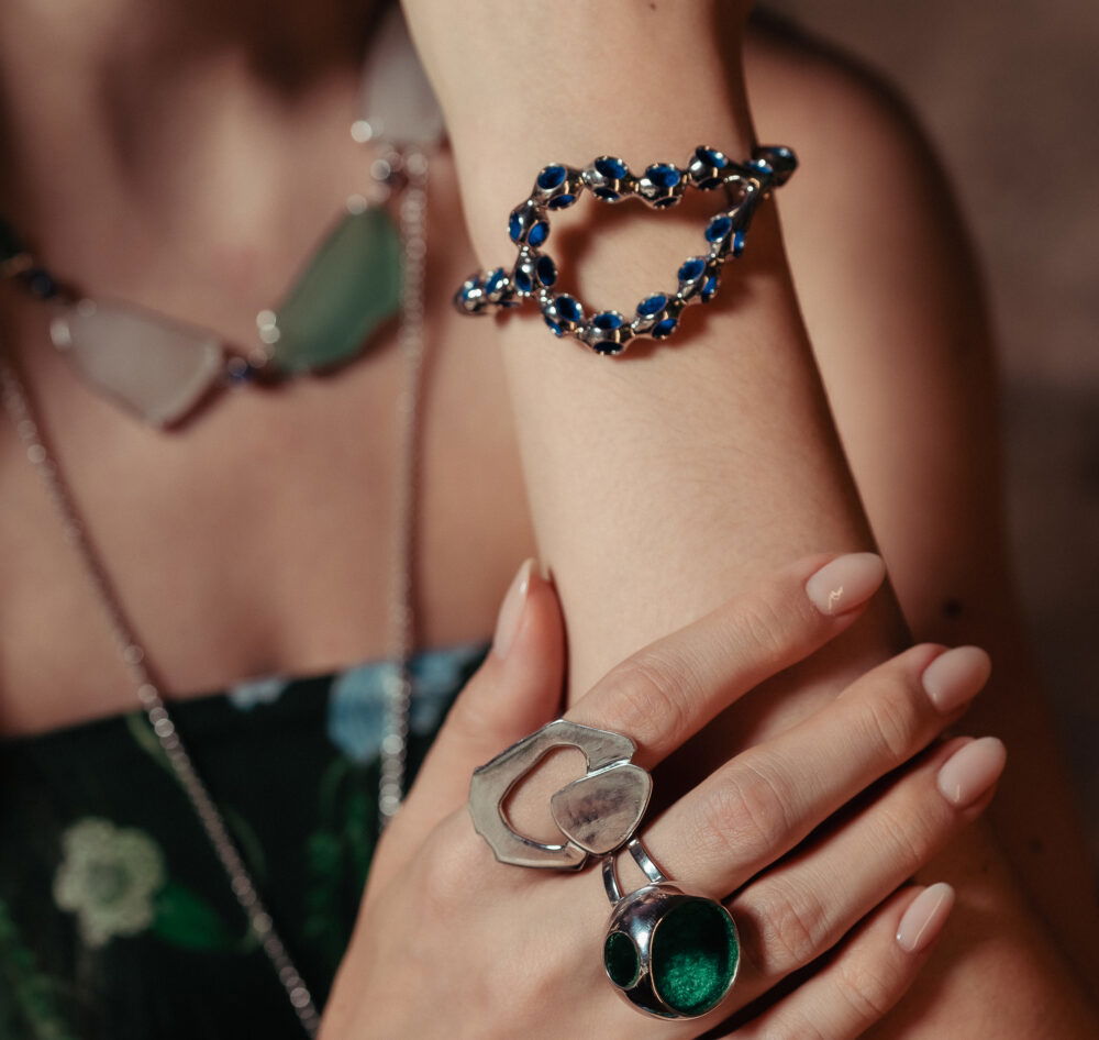 Close-up of stylish blue gemstone cuff bracelet with silver setting on model's wrist.