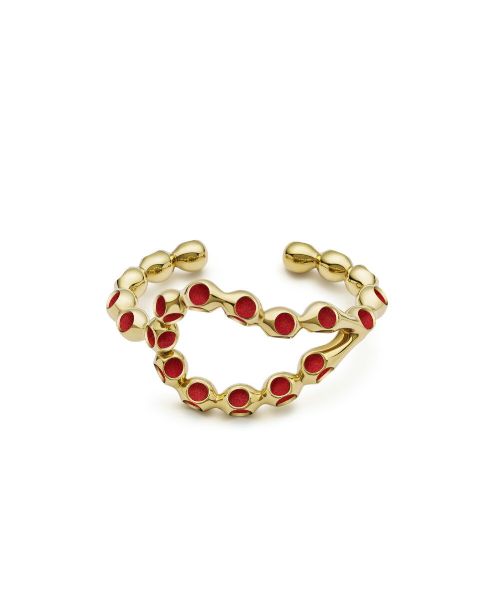 Elegant gold cuff with red accents, stylish jewelry piece for bold fashion statements.