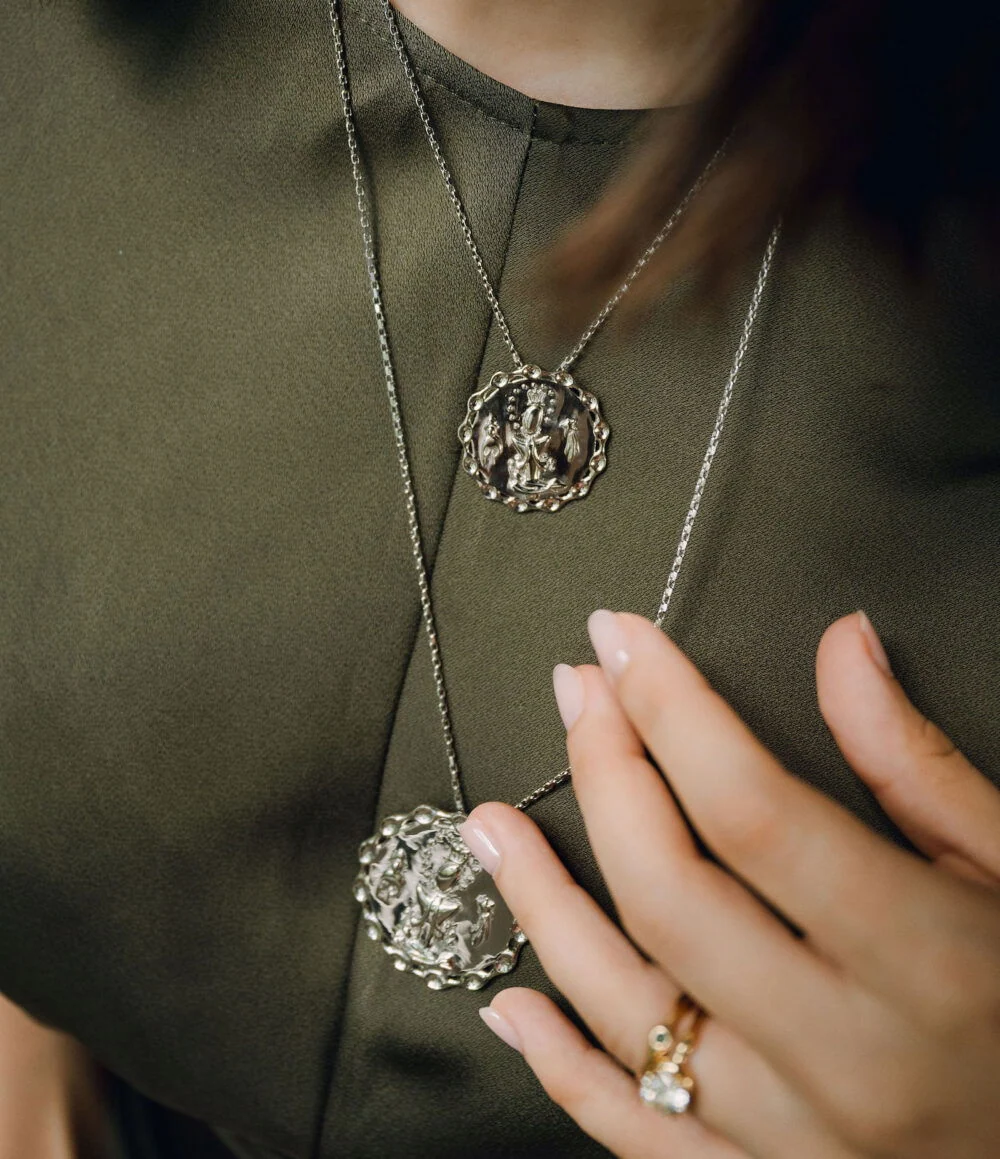 A close-up of a woman wearing a silver La Altagracia medal pendant necklace, showcasing religious jewelry and faith accessories.