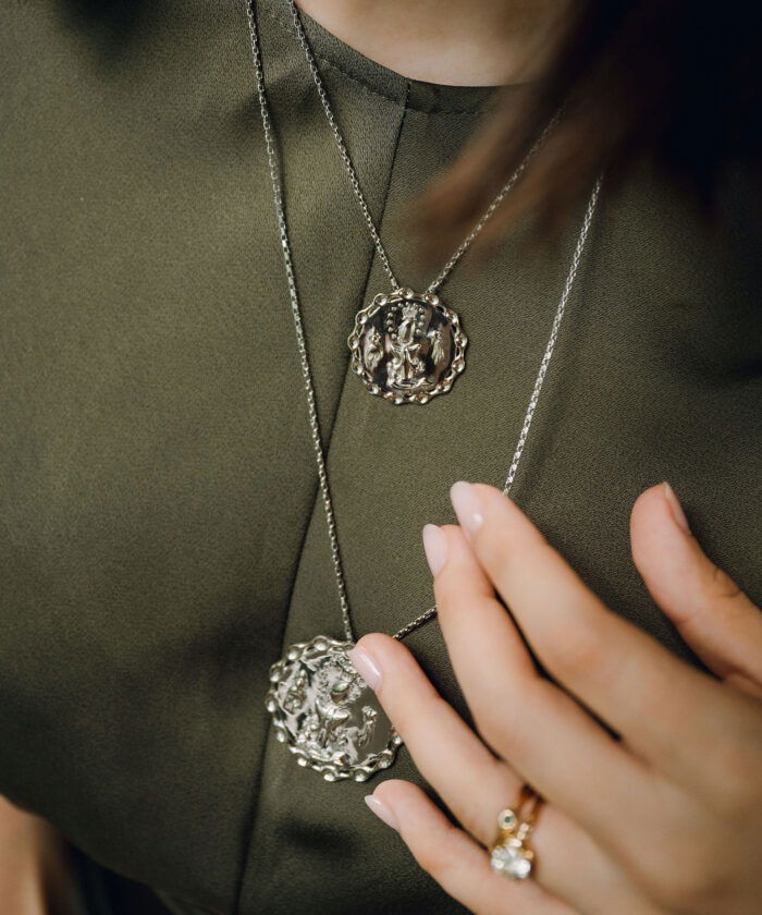 A close-up of a woman wearing a silver La Altagracia medal pendant necklace, showcasing religious jewelry and faith accessories.