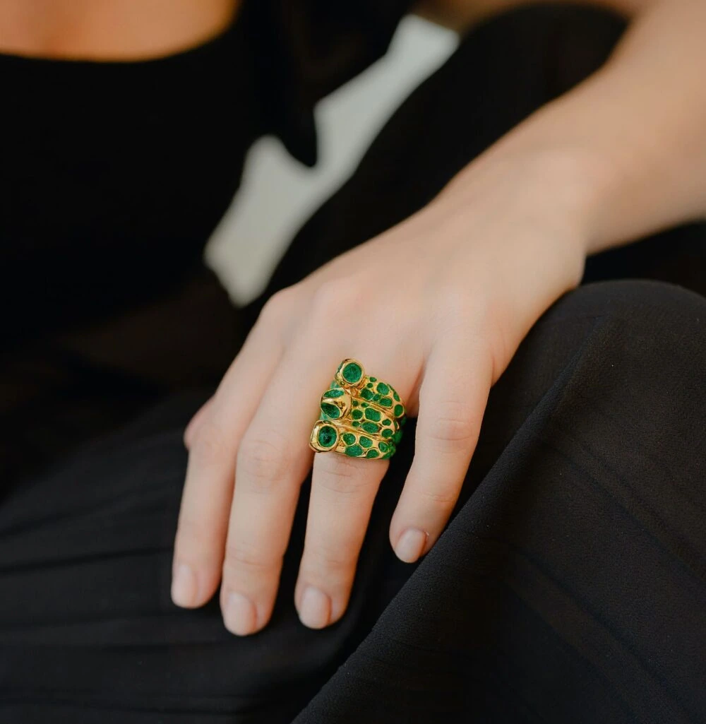 Luxurious gold statement ring with vibrant green gemstones and detailed craftsmanship.