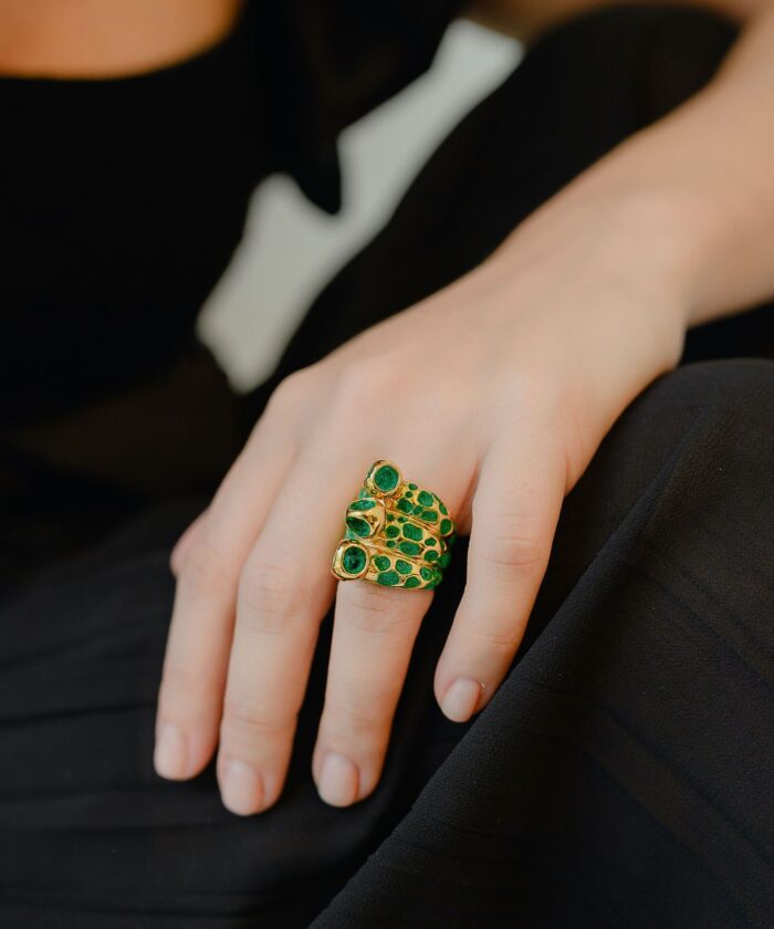 Luxurious gold statement ring with vibrant green gemstones and detailed craftsmanship.