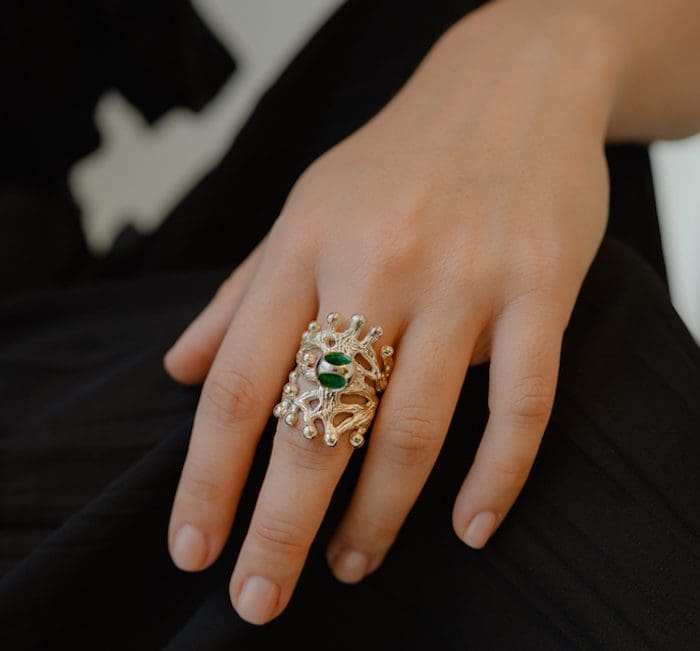 Stunning Monica Varela signature ring featuring an intricate gold and silver design with green gemstones for a luxurious look.