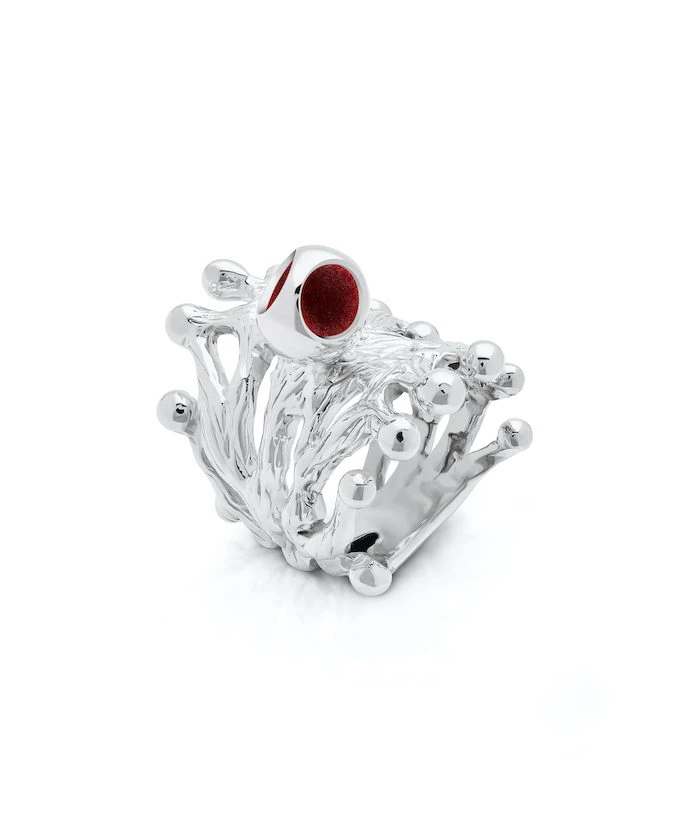 Elegant silver ring with intricate branch design and a striking red gemstone accent.