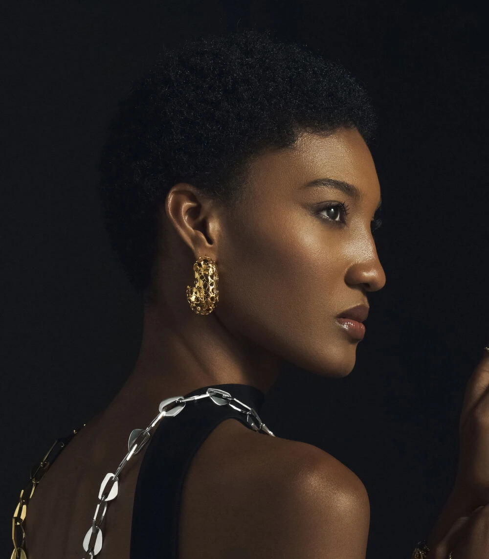 Close-up of stylish gold heritage earrings on a woman with short natural hair, showcasing luxury jewelry.