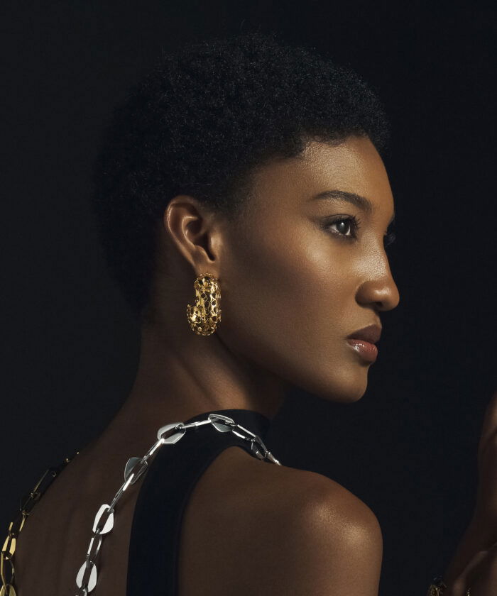 Close-up of stylish gold heritage earrings on a woman with short natural hair, showcasing luxury jewelry.