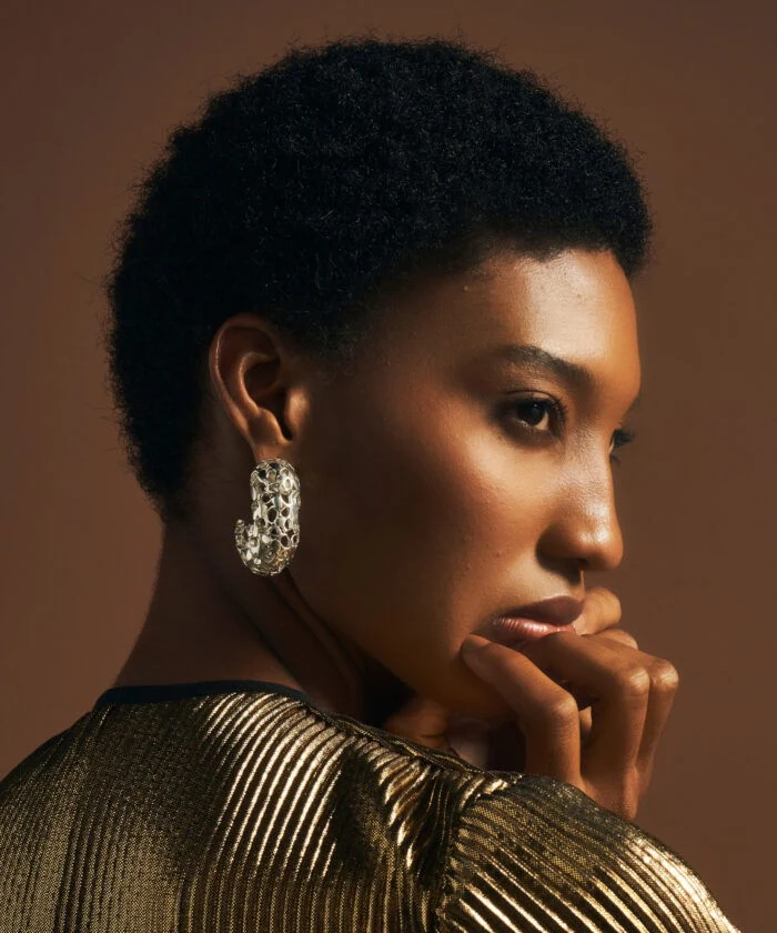 Close-up of a woman wearing intricate gold heritage earrings, highlighting luxury jewelry and sophisticated style.