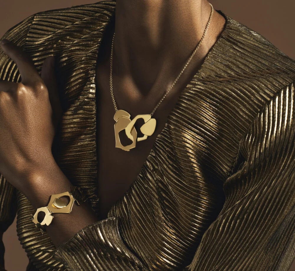 Luxurious gold jewelry set, including a statement necklace and matching bracelet with abstract geometric design.