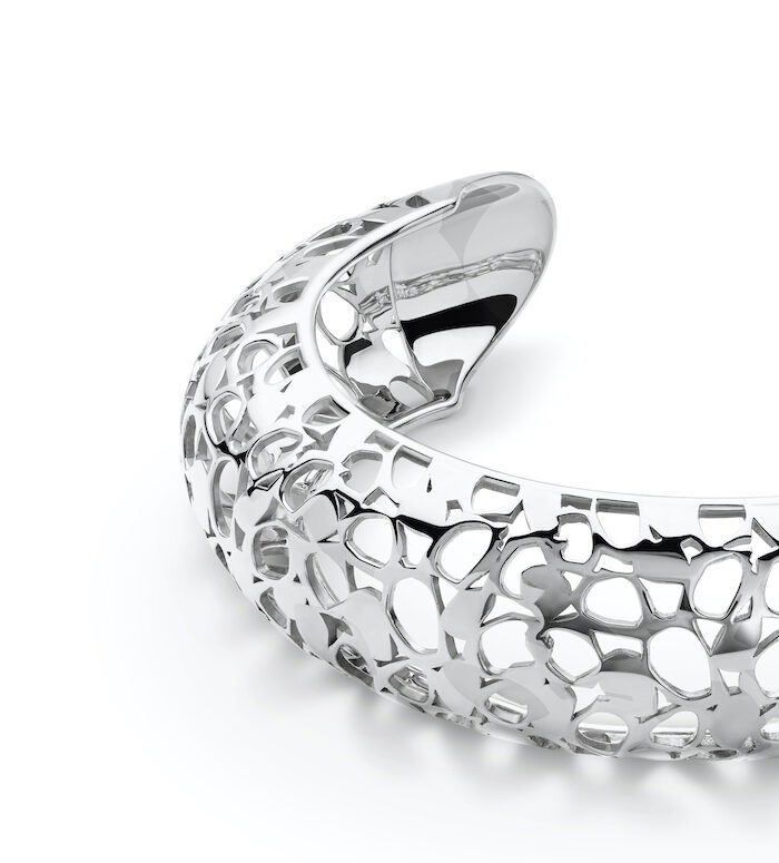 Silver jewelry cuff with intricate cutout design, modern and elegant style.