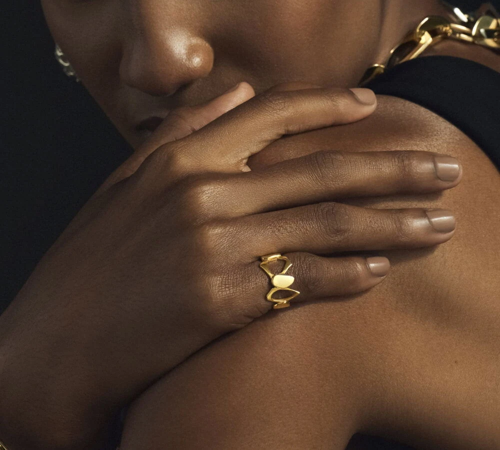 Close-up of a stylish gold heart-shaped ring worn on a woman's finger, emphasizing jewelry elegance.