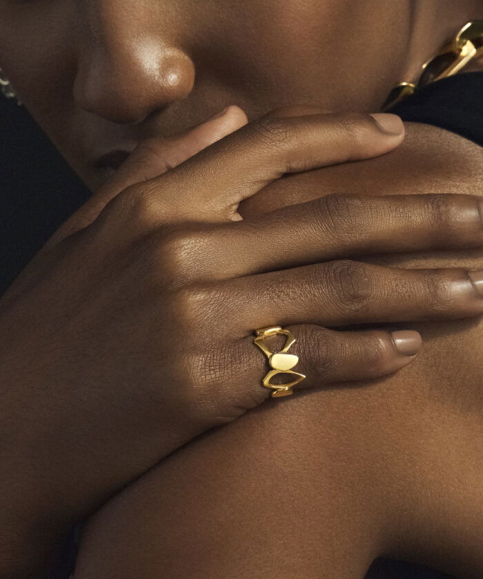Close-up of a stylish gold heart-shaped ring worn on a woman's finger, emphasizing jewelry elegance.