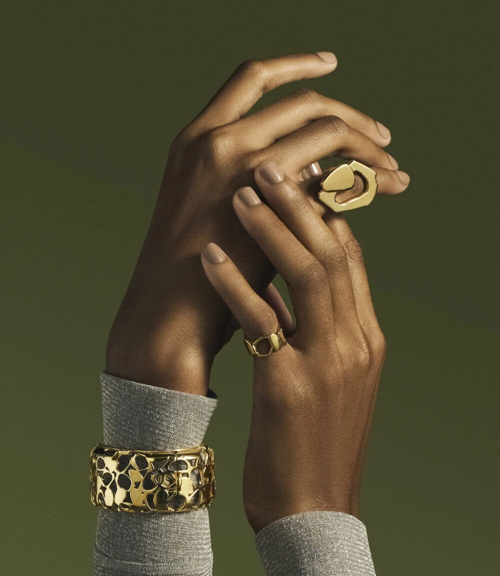 Gold ring and bracelet on dark-skinned hand, showcasing luxurious jewelry and fashion accessories.