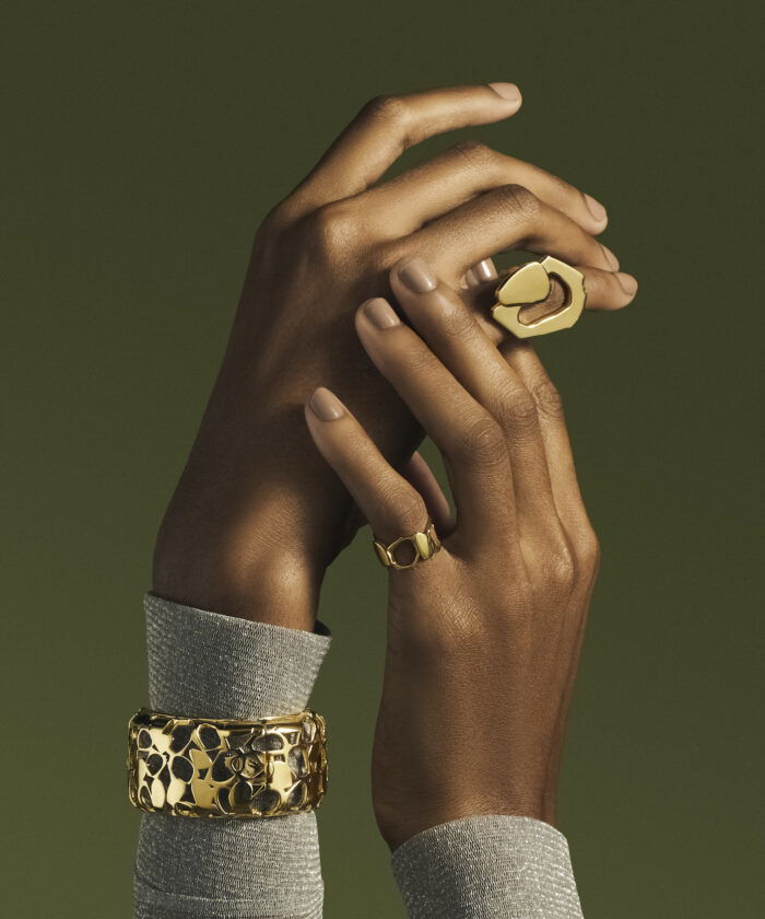 Gold ring and bracelet on dark-skinned hand, showcasing luxurious jewelry and fashion accessories.