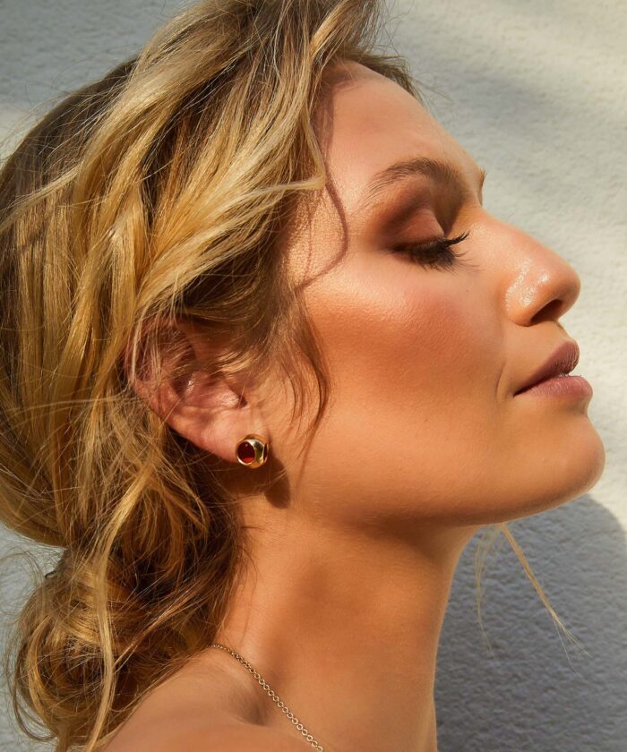 Close-up of Monica Varela wearing elegant small gold earrings.