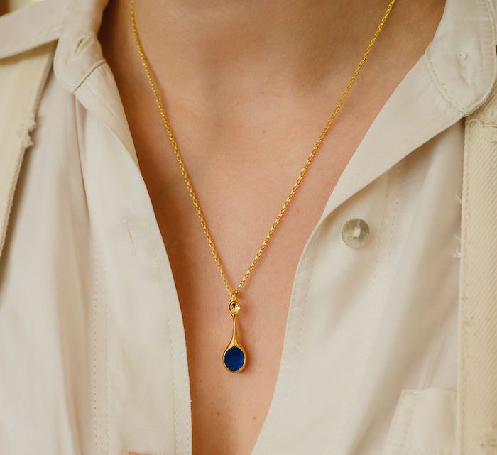 Gold pendant necklace with blue gemstone, perfect for stylish jewelry lovers.