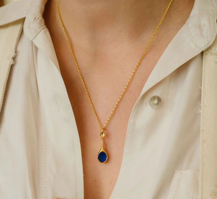 Gold pendant necklace with blue gemstone, perfect for stylish jewelry lovers.