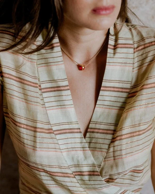 Delicate jewelry featuring a small red gemstone pendant on a fine gold chain. Perfect for everyday elegance.