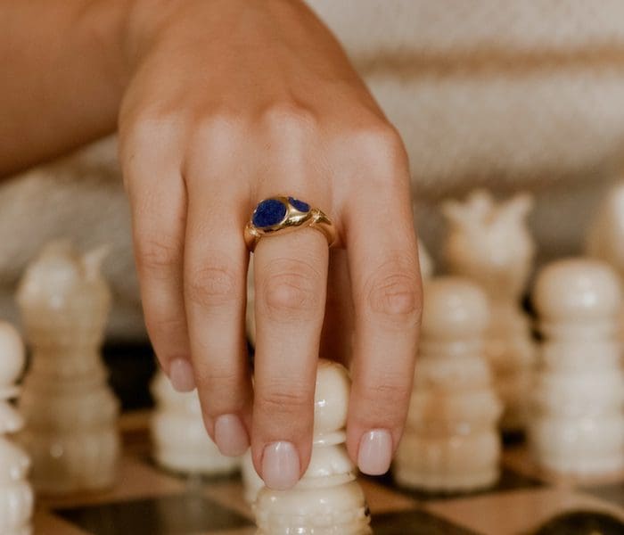 Elegant gold ring featuring a deep blue gemstone, showcased on a finger for a stylish look.