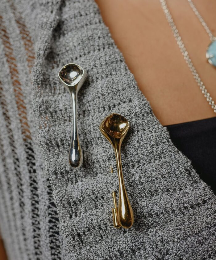 Close-up of elegant silver and gold jewelry pieces on textured clothing.