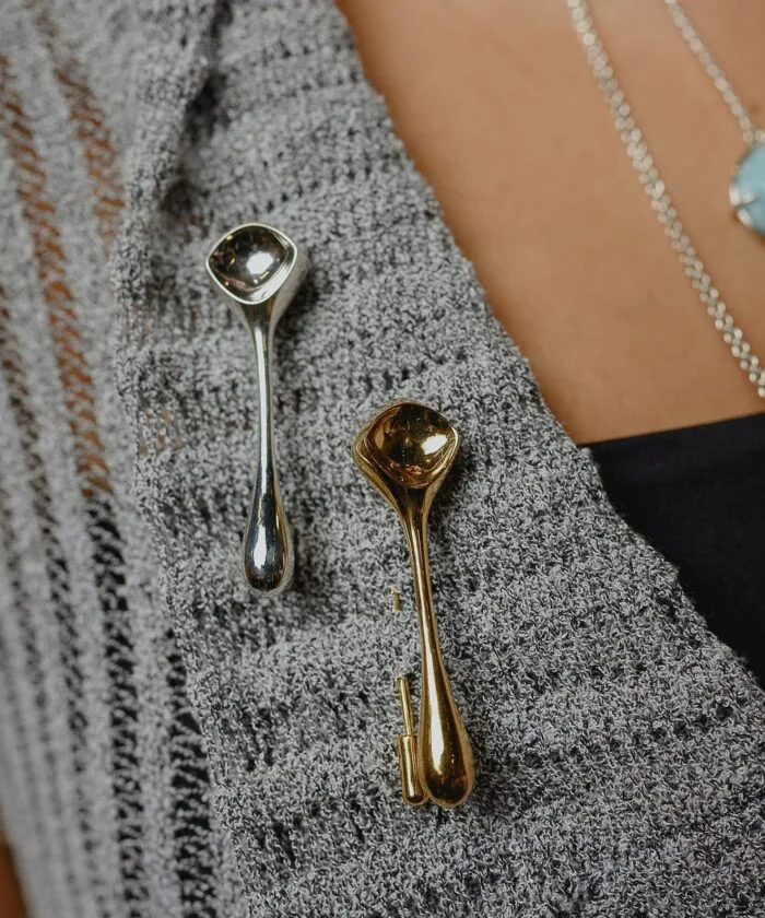 Close-up of elegant silver and gold jewelry pieces on textured clothing.