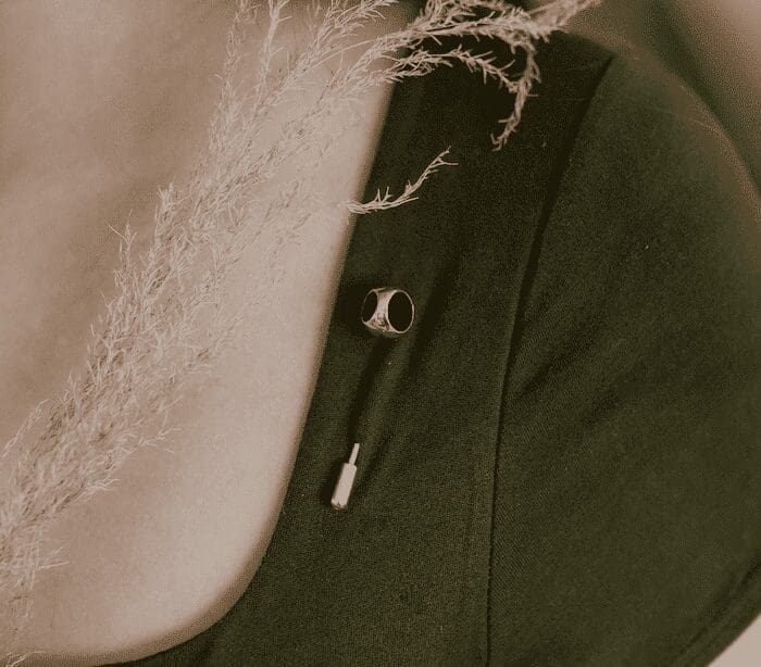 Close-up of black earbuds with silver accents on dark fabric background.