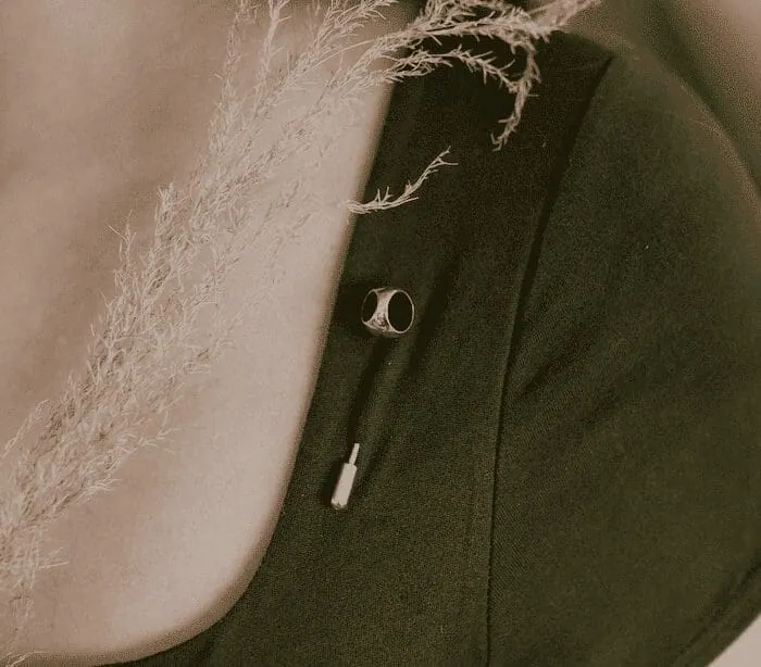 Close-up of black earbuds with silver accents on dark fabric background.