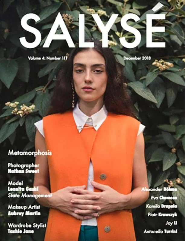 Elegant model Monica Varela on cover of Salysé Magazine wearing vibrant orange vest and white shirt.