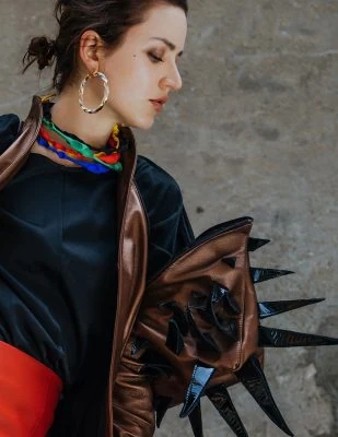 Elegant Monica Varela in stylish attire with bold accessories, showcasing high fashion and edgy style.