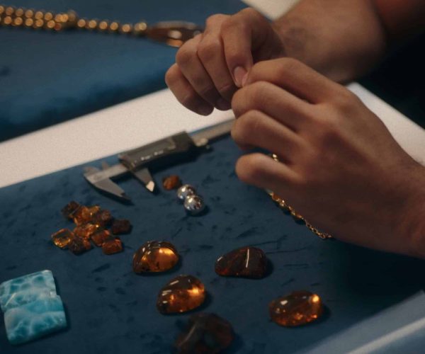 Artisan measuring amber and larimar stones with a caliper