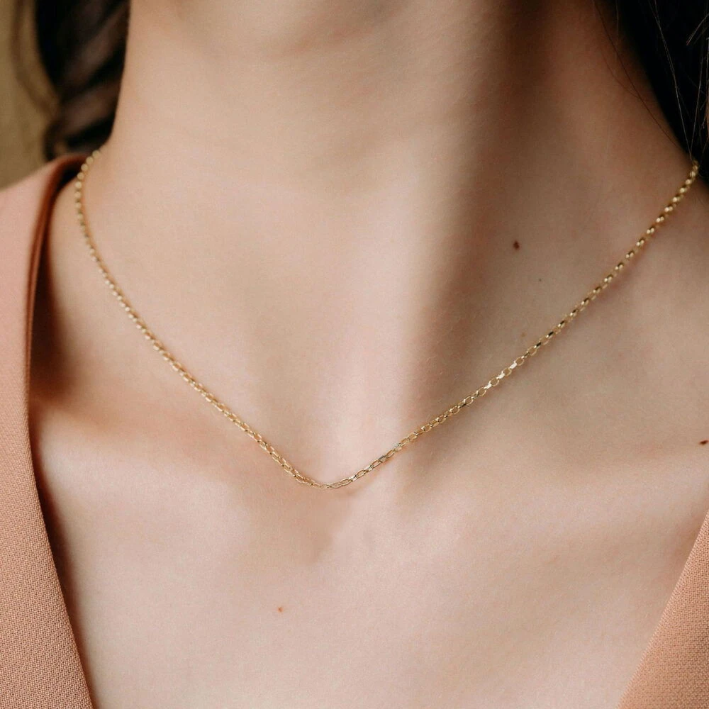 Gold chain necklace with small, elegant links, ideal for casual or formal outfits.