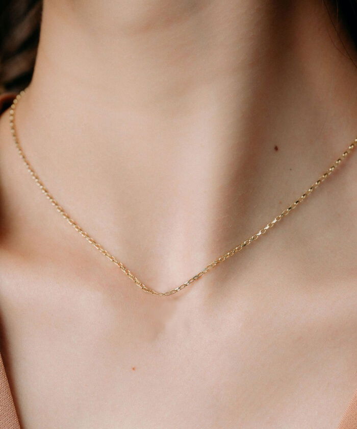 Gold chain necklace with small, elegant links, ideal for casual or formal outfits.