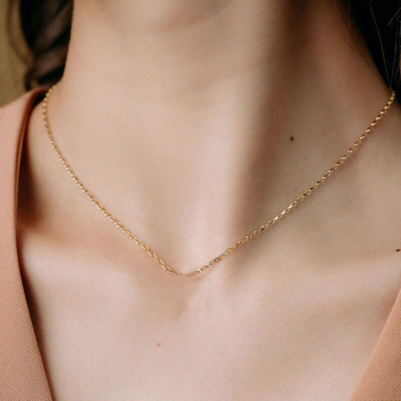 Gold chain necklace with small, elegant links, ideal for casual or formal outfits.