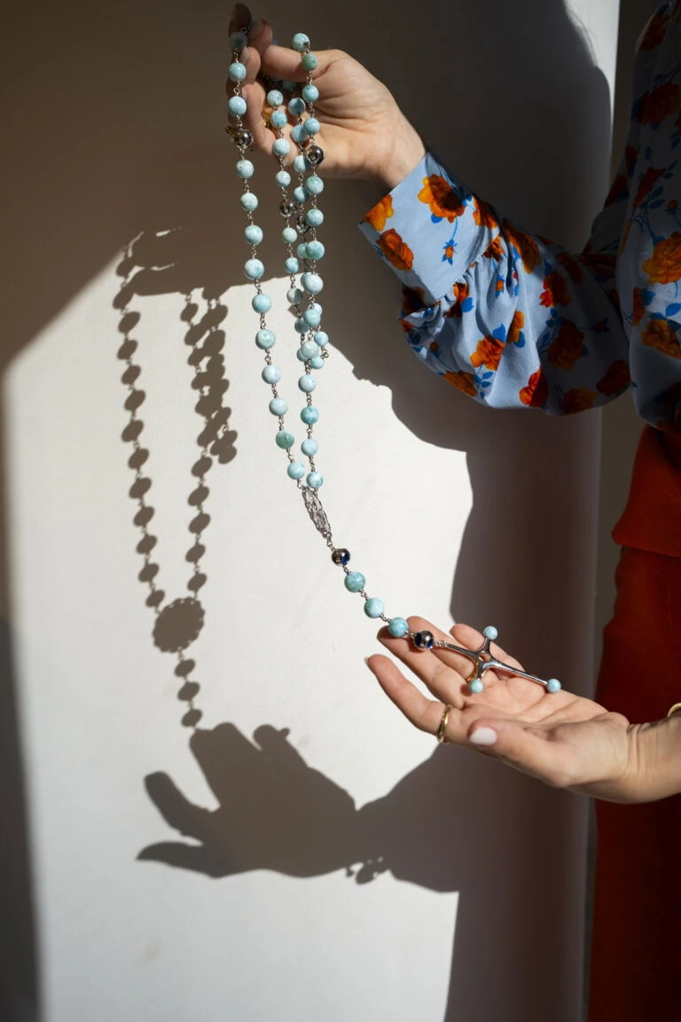 Beautiful larimar rosary crafted by designer Monica Varela, featuring turquoise beads and intricate silver details, inspired by religious artistry.