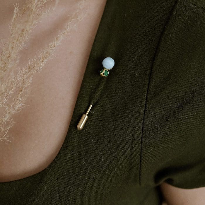 Delicate Larimar gemstone jewelry pin on fashionable clothing accessory.