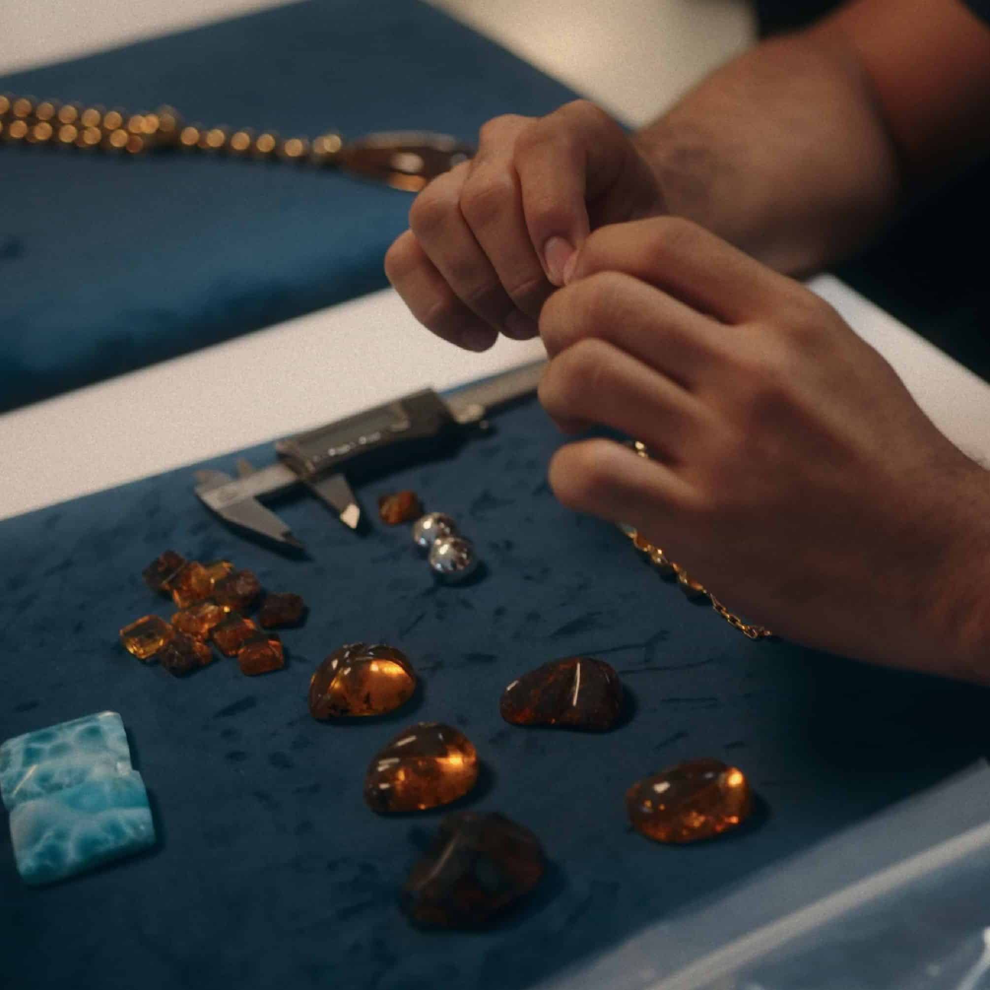 Artisan measuring amber and larimar stones with a caliper